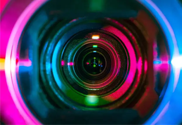 A camera lens with colorful lights reflecting off it.